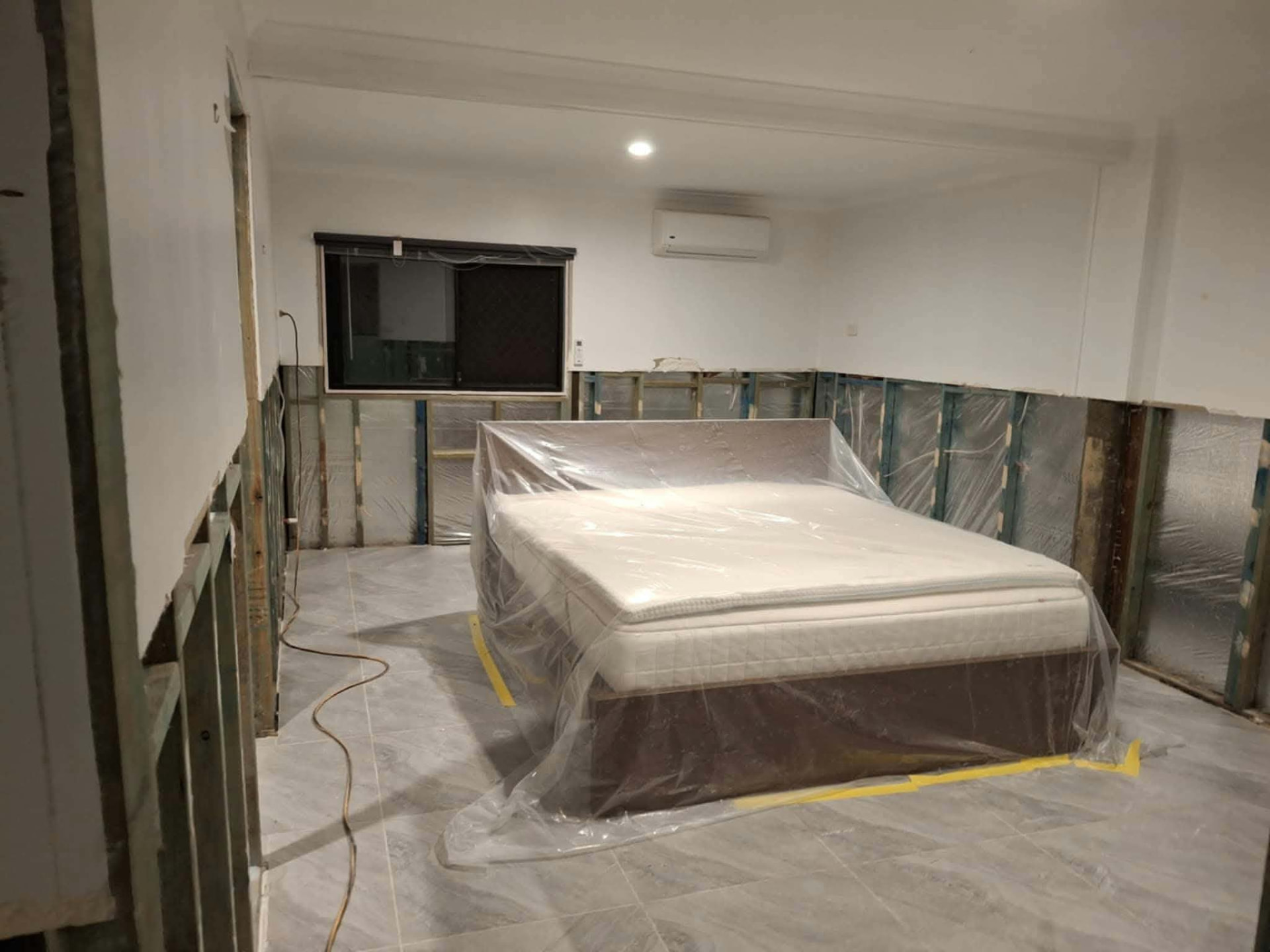 Bedroom contents wrapped in plastic and wall linings removed inside a containment area
